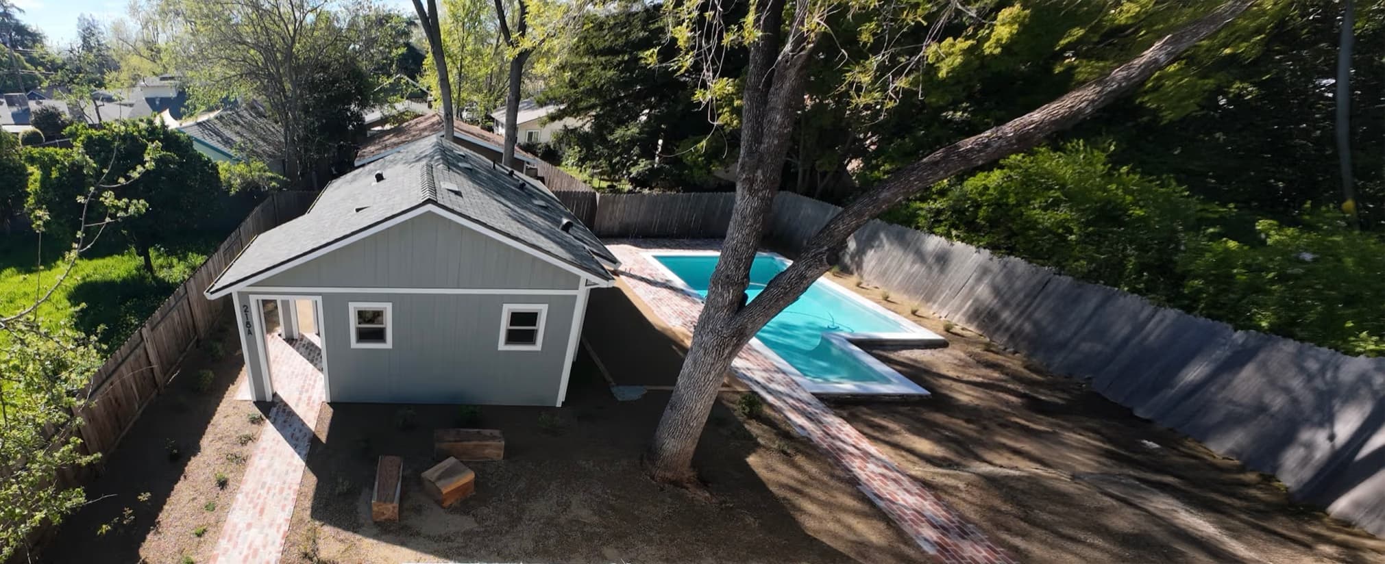 Drone aerial of a finished detached backyard ADU with shingle roof beside the main Roseville home and patio