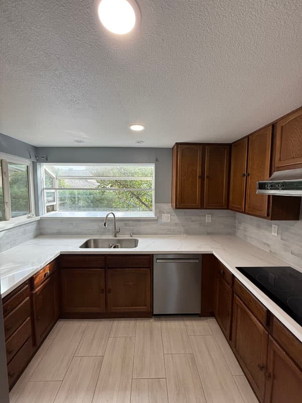 Wide view of a finished Sacramento kitchen remodel with white shaker cabinets, quartz island and stainless appliances